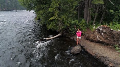 Female-hiker-standing-near-river-4k