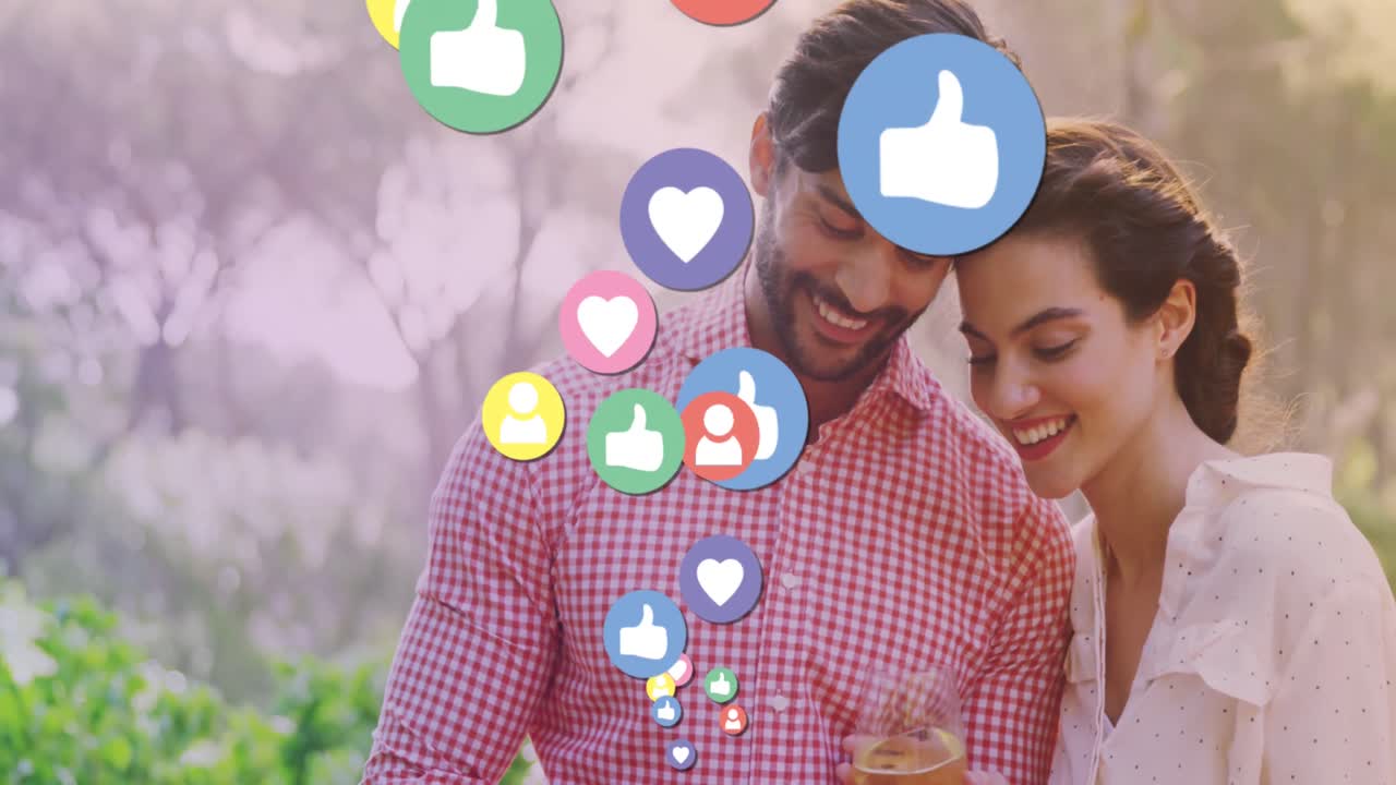animación de iconos de los medios sobre una feliz pareja biracial usando un teléfono inteligente