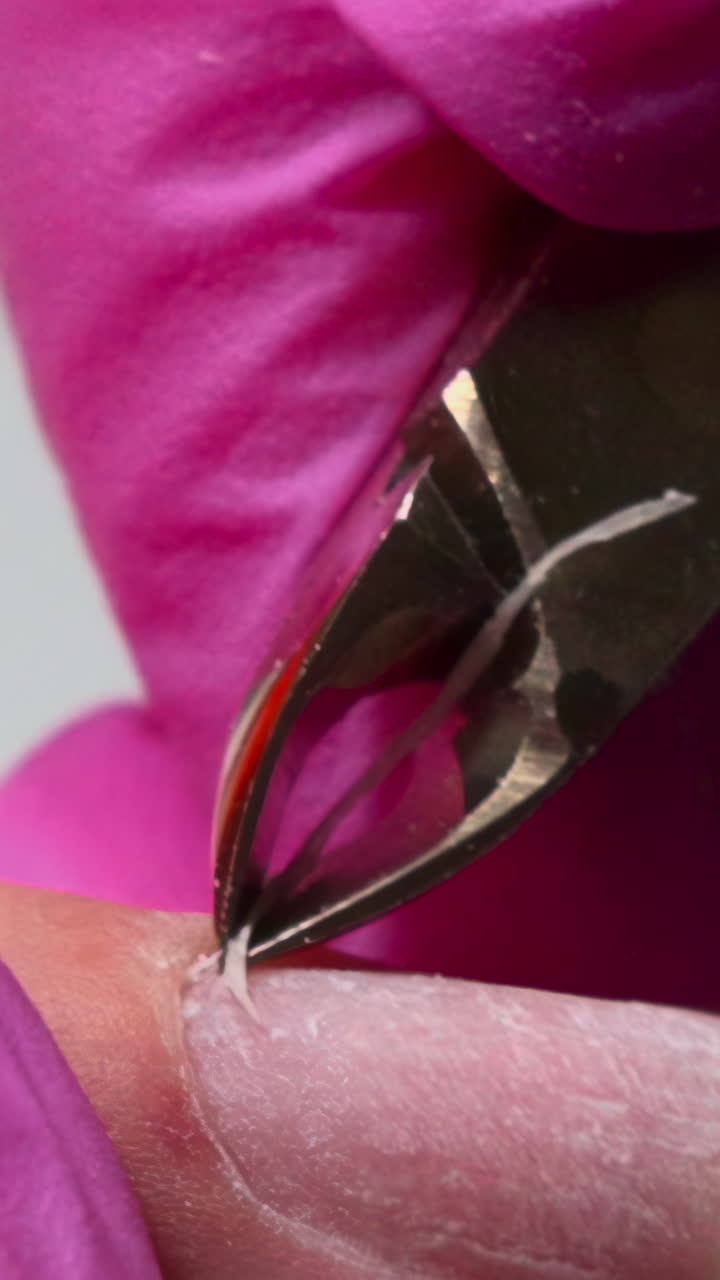 Nahaufnahme einer Person beim Kürzen der Nagelhaut mit einer Zange