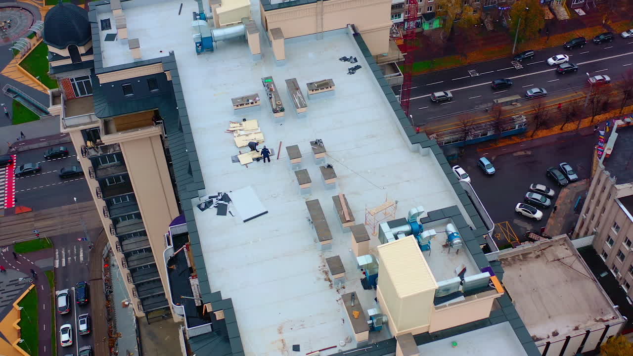 Roof of multistorey building under construction. Modern apartment house builds in the city. Workers build the tower building. Top aerial view.
