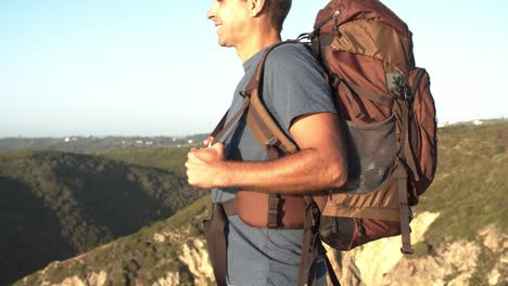 Male-backpacker-standing-at-rocky-cliff