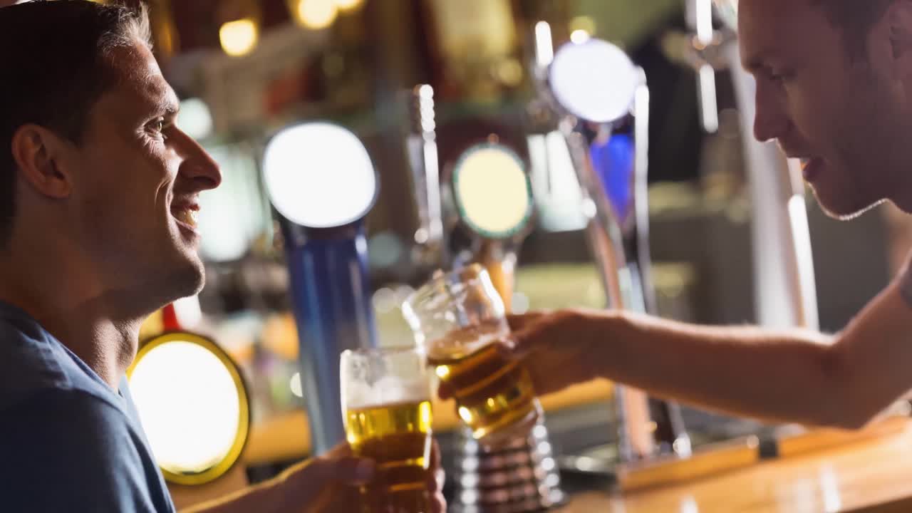 felices amigos caucásicos sonriendo y haciendo un brindis en el bar