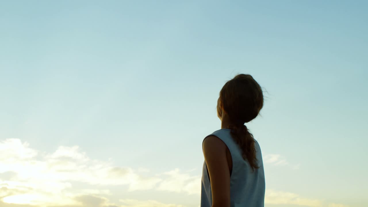 mujer de pie con los brazos en la playa 4k