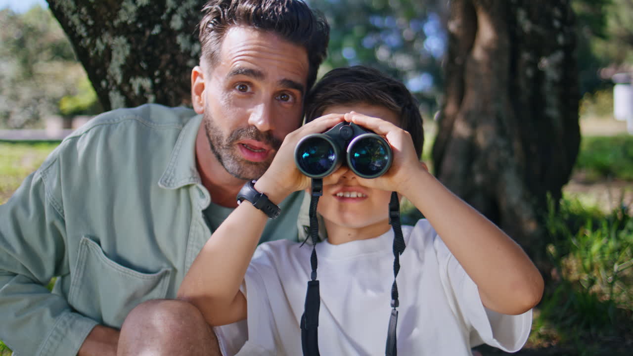Father son enjoying birdwatching on sunny day closeup. Kid staring binoculars