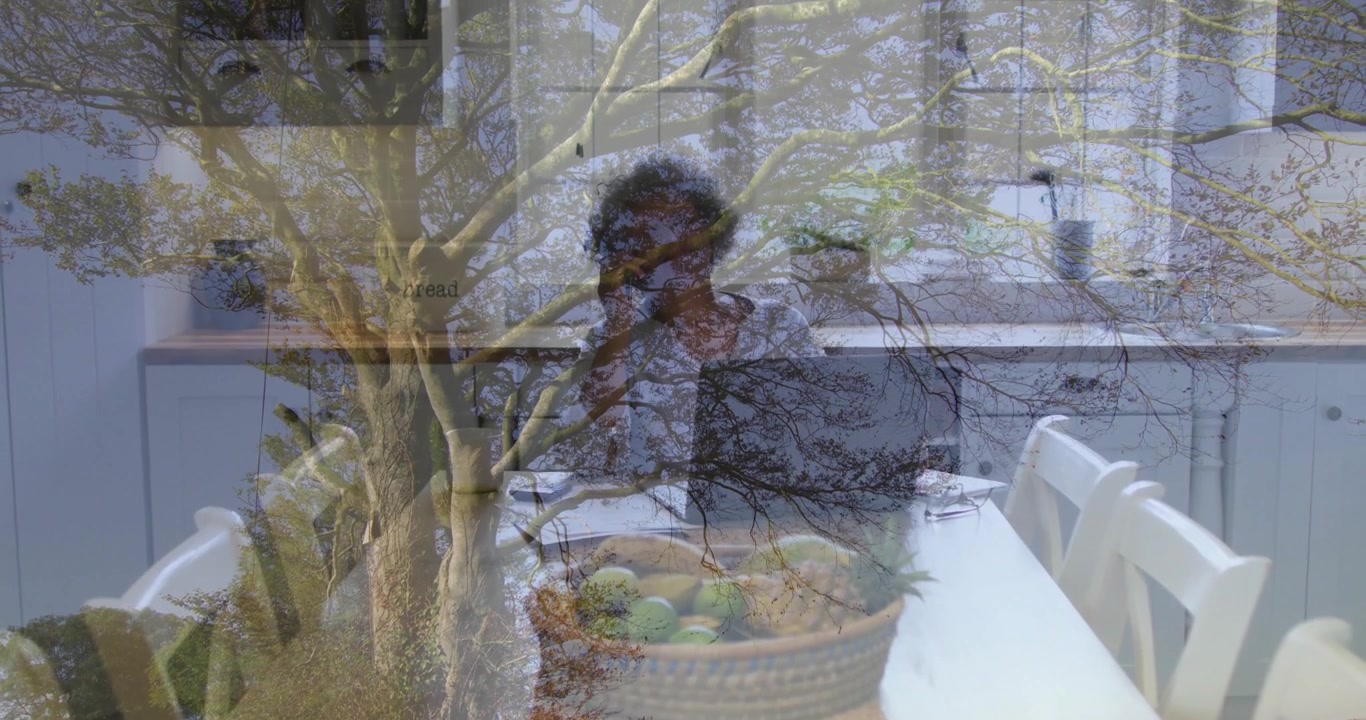 Animation of tree branches blending with kitchen scene, person sitting at table
