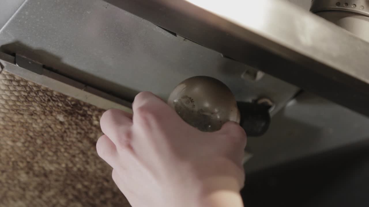 깨진 전구를 천천히 비틀고 제거하는 손 - 클로즈업 샷