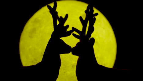 miniature reindeer couple kissing against yellow moonlight backdrop