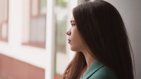 woman looking out window with sad expression