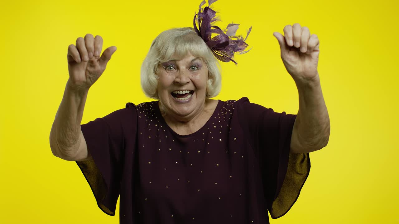 Extremely happy satisfied senior old woman with blond hair celebrating victory with smile, success