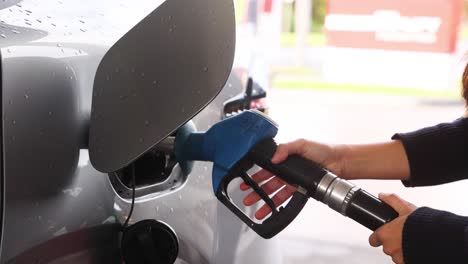 person refueling car at gas station