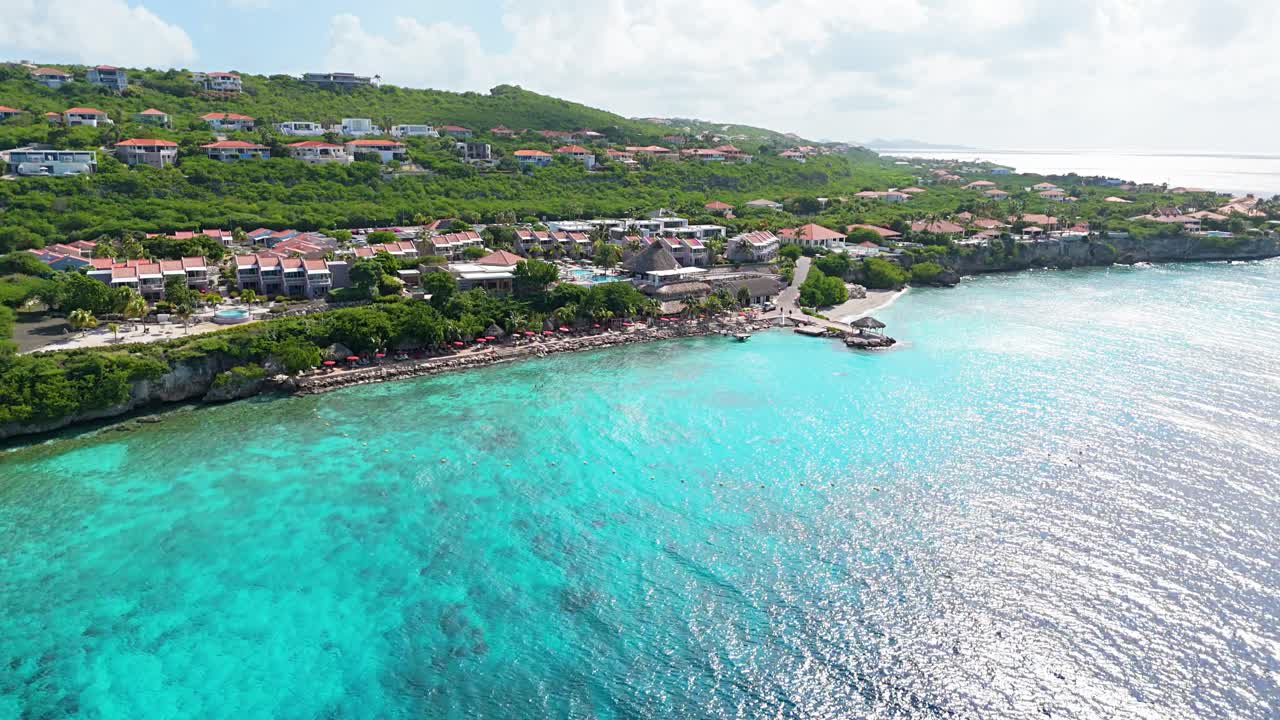 Panoramisk drone stiger opp over fantastisk klart blått havvann for å avsløre luksusvillaer
