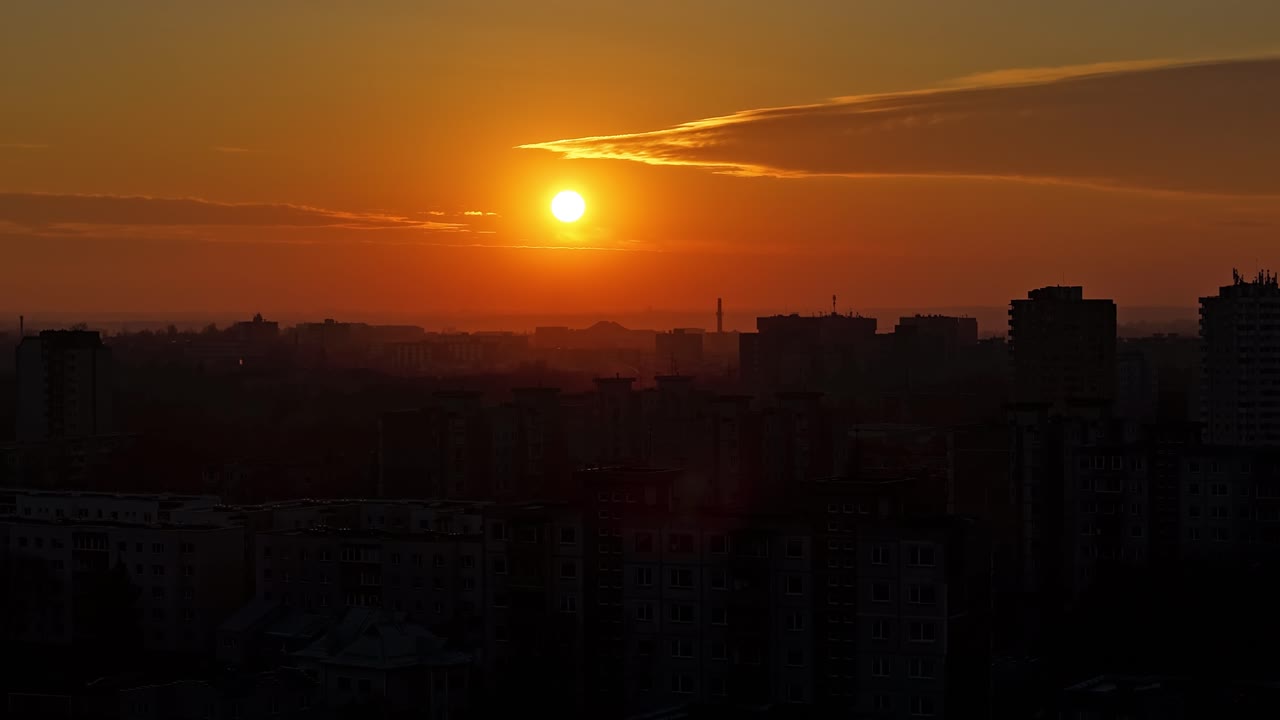 Deep orange sunset over silhouette of Kaunas city buildings, aerial time lapse