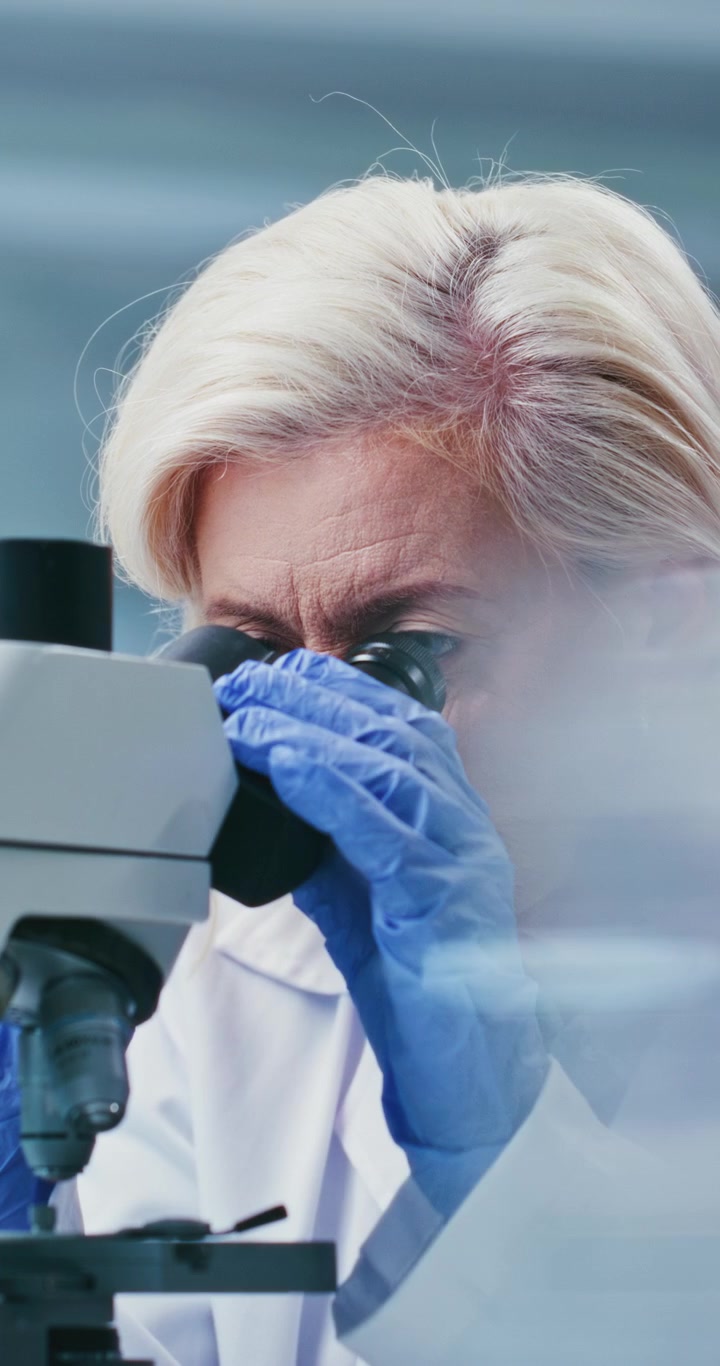 Scienziata matura che esamina campioni al microscopio in laboratorio