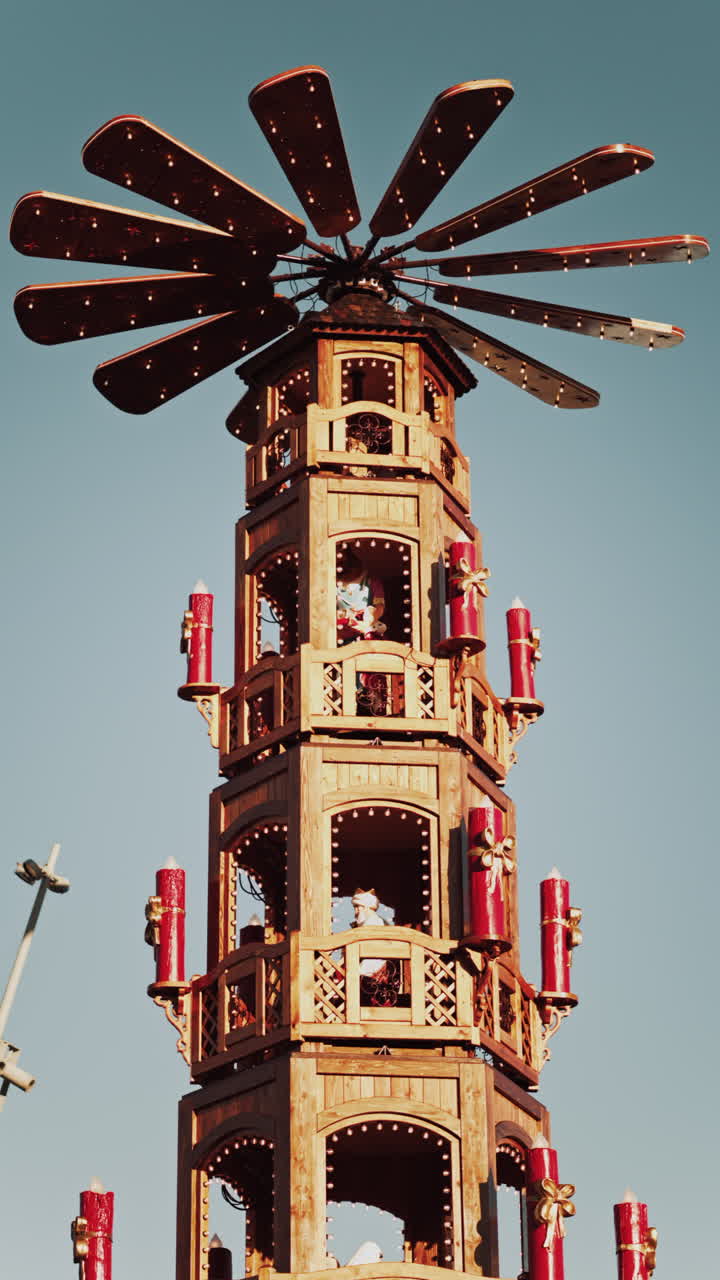 Traditional wooden Christmas pyramid against a clear blue sky with levels representing nativity scenes at a Christmas market in France. Vertical