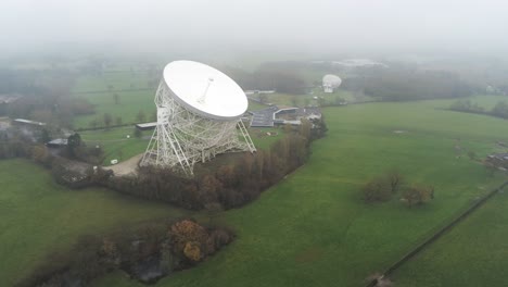 Aerial-Jodrell-bank-observatory-Lovell-telescope-misty-rural-countryside-pull-back-orbit-left