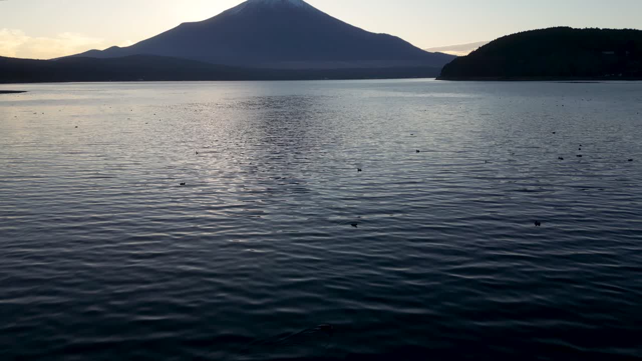 Low angle slow motion tilt up reveal of Mt. Fuji from drone at sunset