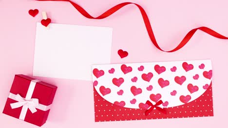tarjeta de día de san valentín con sobre, regalo y cinta en tema rosa.