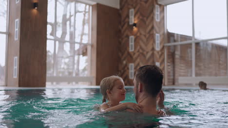 una niña feliz está jugando con su padre en el área de recreación de la piscina y el centro de bienestar para la familia