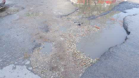 carretera de asfalto mojada y rota con baches, vista en movimiento
