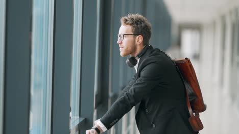 Excited-young-man-standing-in-the-hallway-by-the-window-talking-to-himself