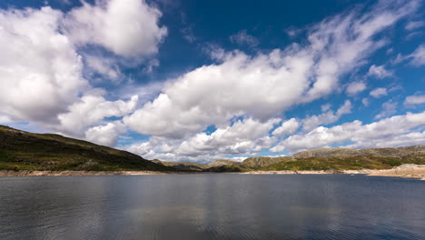 Fluffy cloud movement in big blue sky over lake - time lapse