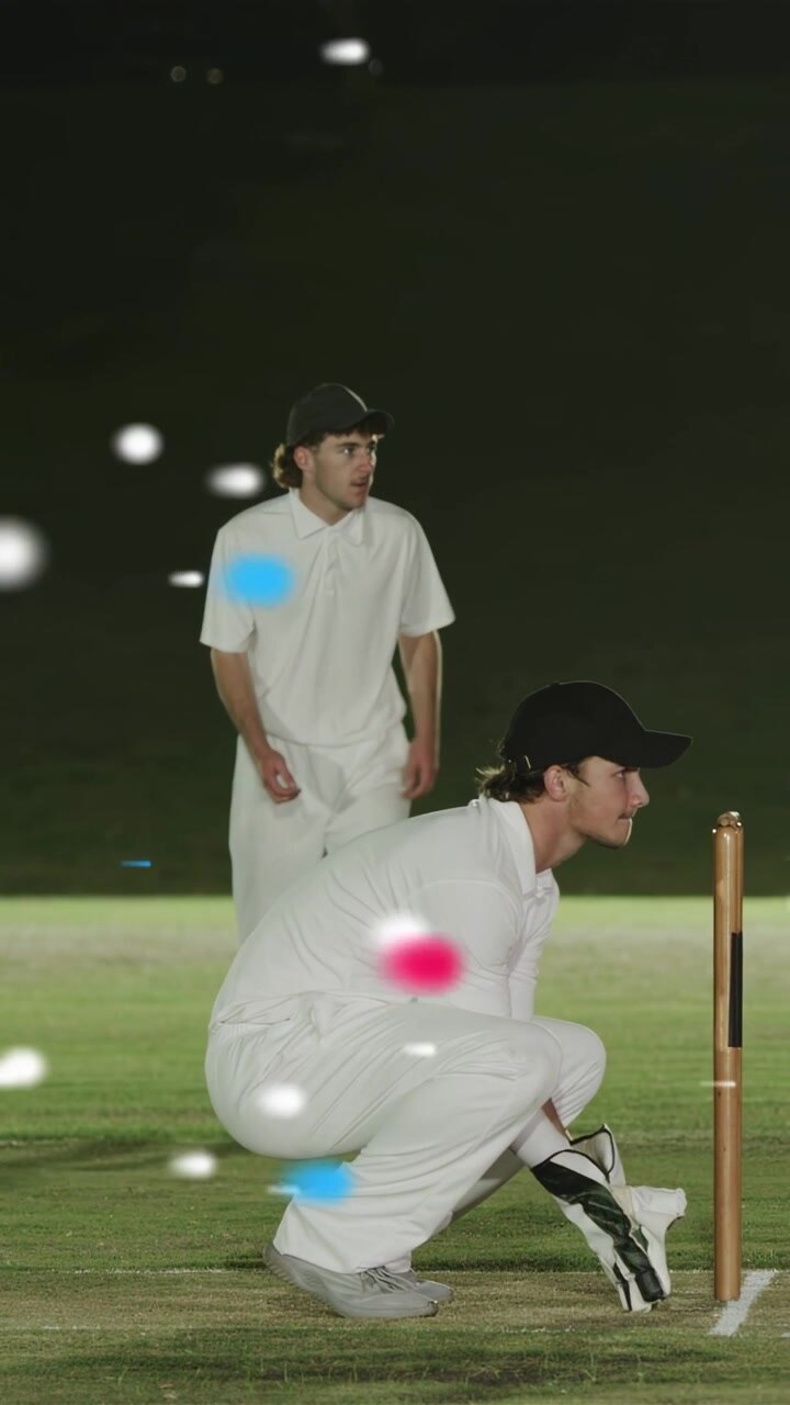 Video verticale: Wicket-keeper di cricket che afferra la palla e la assicura nei guanti ai paletti, preparando la palla con effetto bokeh.