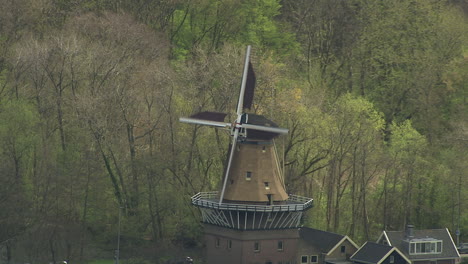 Aerial-shot-of-traditional-dutch-windmills-turning-at-the-side-of-a-lake-in-downtown-Rotterdam