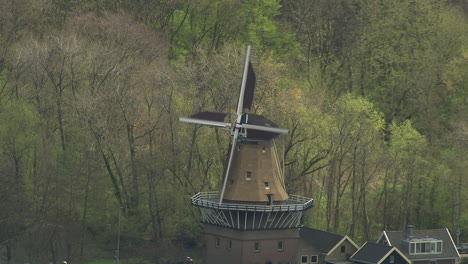 aerial shot of traditional dutch windmills turning at the side of a lake in downtown rotterdam