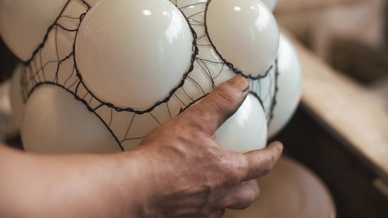 Mano dell'artigiano che ruota un oggetto sferico bianco con reticolato nero