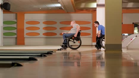 two young disabled men in wheelchairs playing bowling in the club