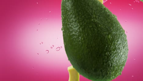 aguacate con rebanadas y salpicaduras cayendo sobre un fondo rosado