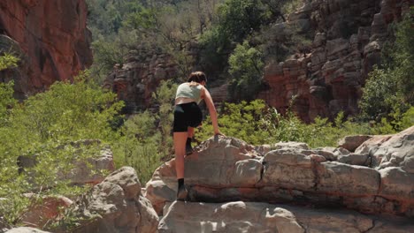 joven mujer caucásica subiendo rocas en el valle del paraíso, agadir, marruecos