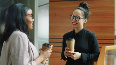 multiethnic businesswomen chatting on coffee break in office