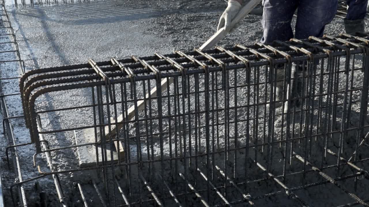 workers apply a layer of cement to create the floor and roof of a large area under construction