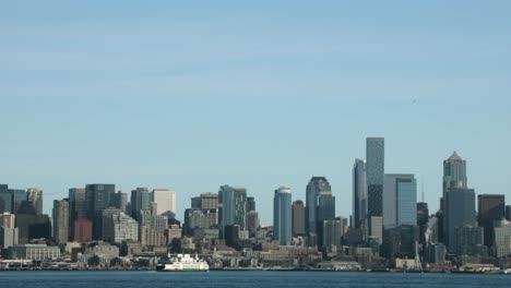 Transbordador-Navegando-En-Aguas-Tranquilas-Con-Edificios-Frente-Al-Mar-En-El-Fondo---Vista-Desde-El-Oeste-De-Seattle,-Washington---Toma-Estática