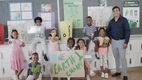 portrait of diverse teacher and schoolchildren with ecology models and texts at elementary school