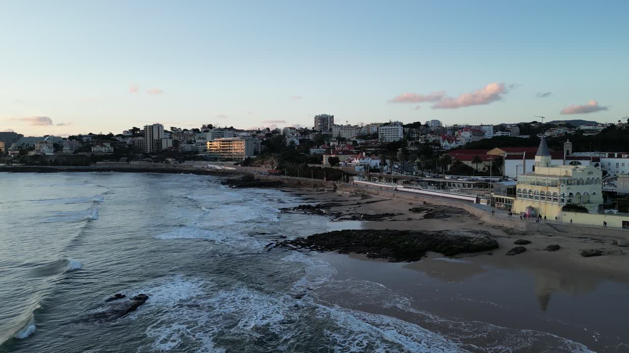 Vista Aerea della Spiaggia di una Città Costiera al Tramonto con Onde che si Infrangono