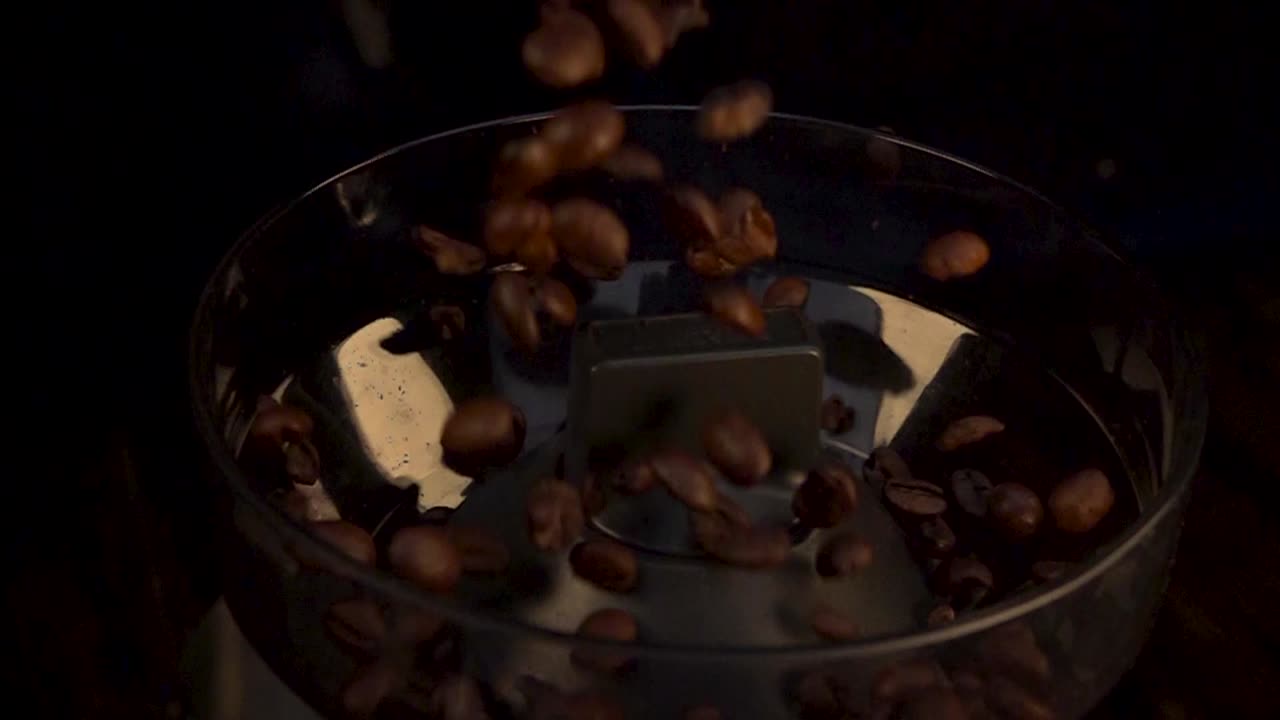 Coffee Beans falling down a bean grinder machine at slow motion.