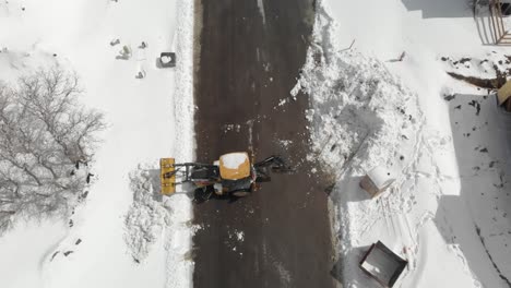 Vista-Aérea-Vertical-Del-Cargador-Frontal-Limpiando-La-Carretera-De-Nieve-Profunda