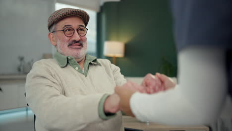 elderly man holding hands with a caregiver