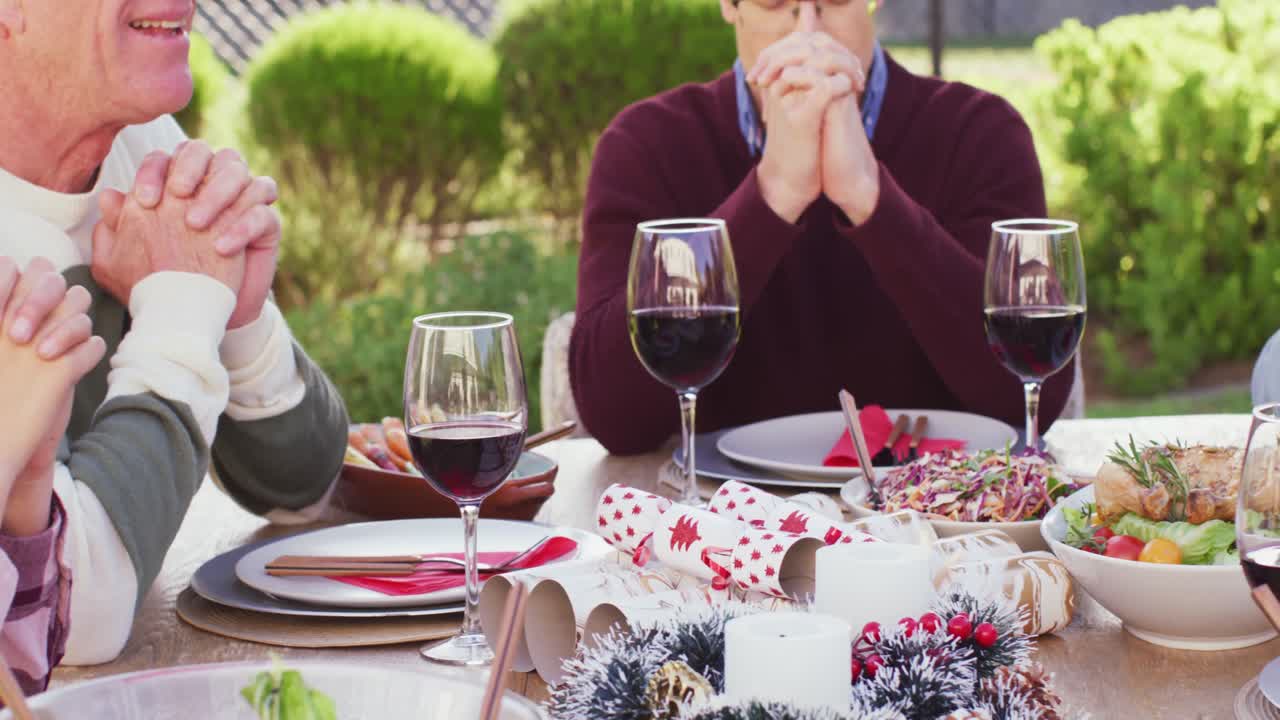 행복한 백인 가족이 정원에서 저녁 식사 전에 기도하고 있습니다.