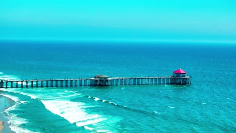 drove view of the pier in huntington beach with large waves breaking on shore