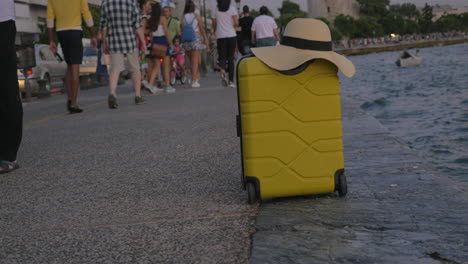 maleta con verano en el sombrero en el paseo marítimo abarrotado