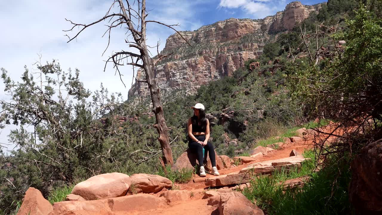 Jeune femme souriante se reposant sur un sentier de montagne désertique