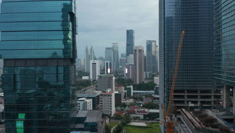 Aerial-forward-flight-towards-downtown-city-skyscrapers-between-two-glass-skyscrapers-in-Jakarta,-Indonesia