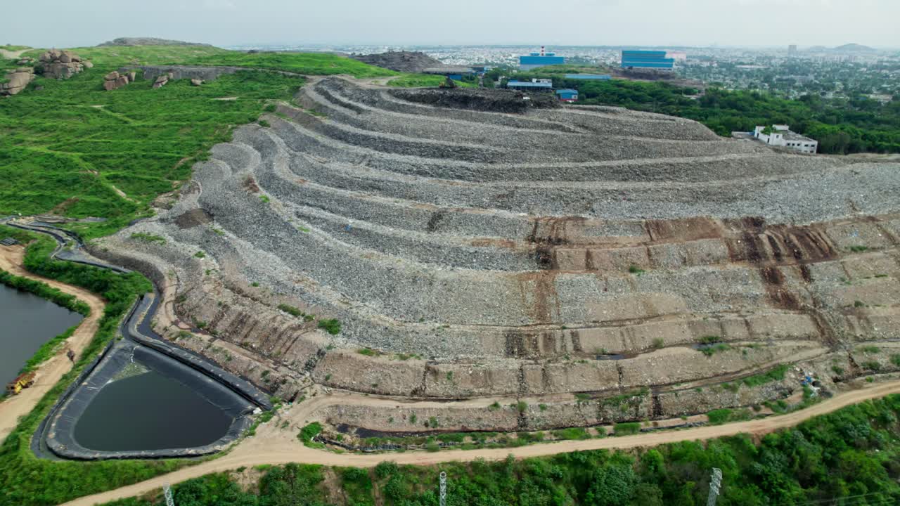 Hyderabad Integrated Municipal Solid Waste plant with city scape and large size of dumpyard at Balaji Nagar, hyderabad, india. day time, push back shot, drone shot, 4k