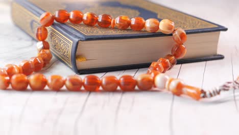 quran and rosary on wooden table