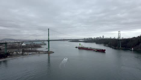 cargo ship passing under lions gate bridge, vancouver in canada