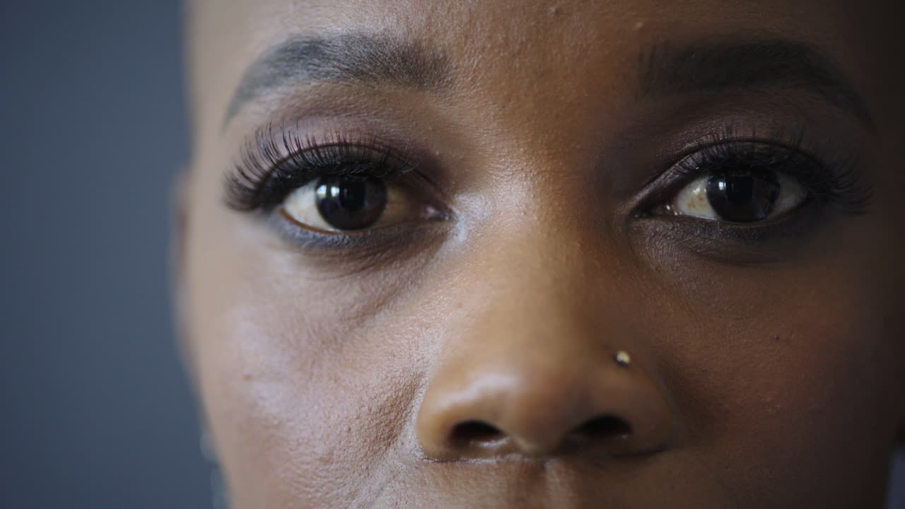 clip de una hermosa mujer afroamericana abriendo los ojos mirando a la cámara usando maquillaje perforación de la nariz