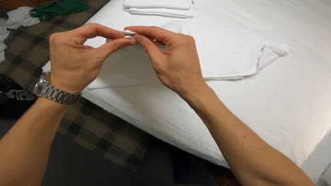 First-person-pov-of-man-folding-and-rolling-white-towels-to-place-on-hotel-bed